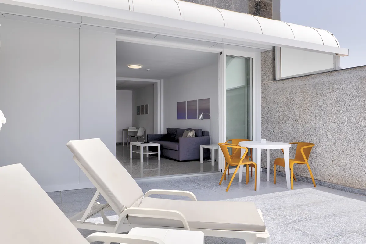 Terraza moderna con tumbonas y set de mesa con sillas anaranjadas.