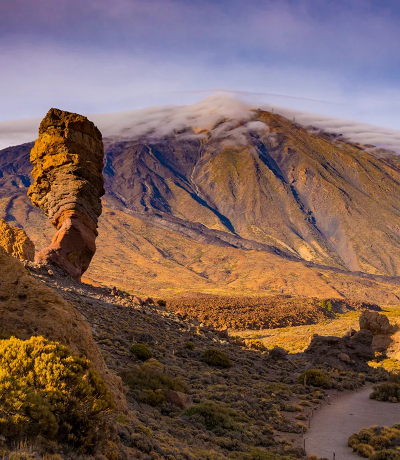 Formaci&oacute;n rocosa con un monte y nubes en un paisaje &aacute;rido y monta&ntilde;oso.