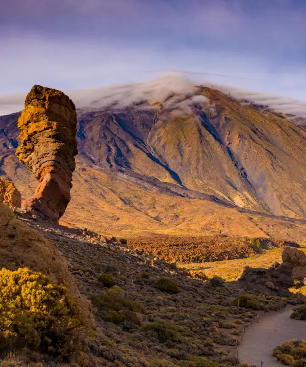 Paisaje monta&ntilde;oso con roca prominente y nubes en el cielo.