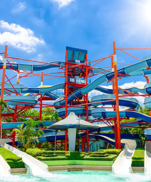 Toboganes de agua con estructuras rojas en un parque acu&aacute;tico soleado.