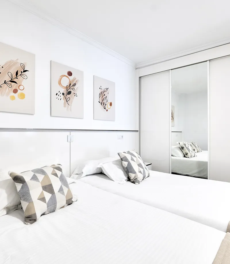 Habitaci&oacute;n moderna con camas gemelas, arte en las paredes y cojines geom&eacute;tricos.