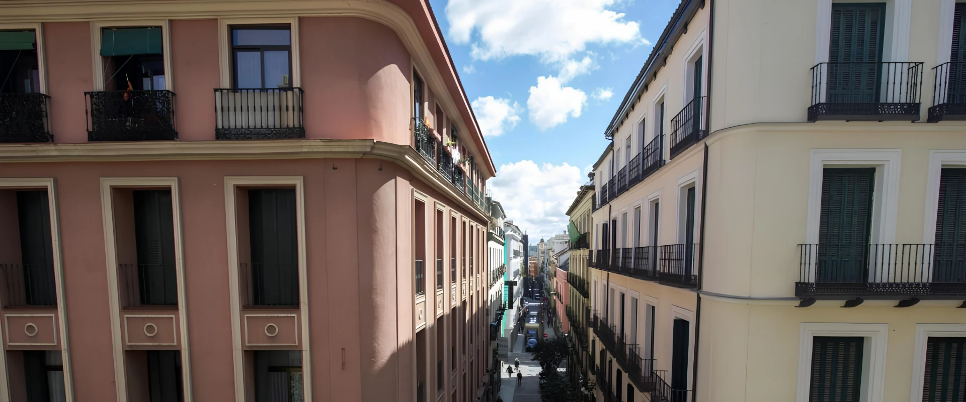 Calle estrecha con edificios a cada lado y cielo azul con nubes.