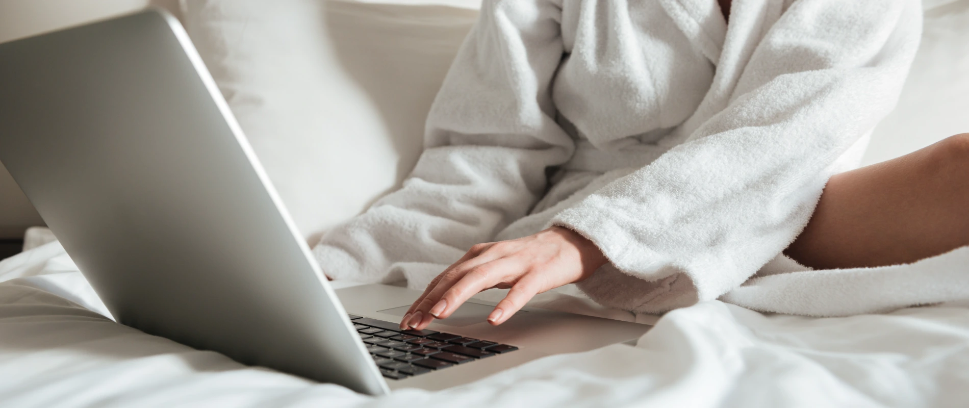 Persona en bata usando una laptop en la cama.