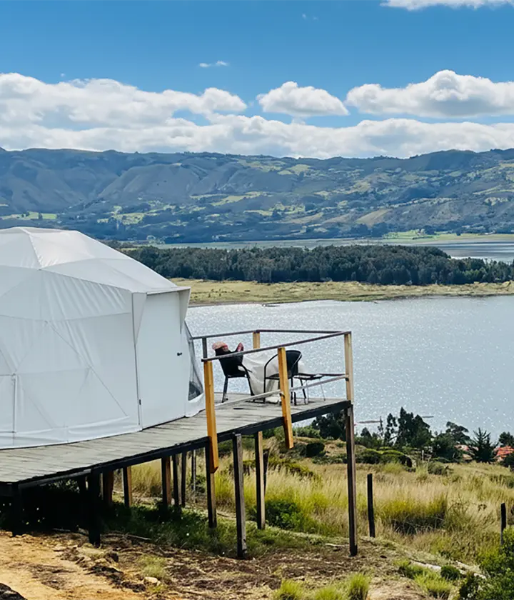 Domo blanco junto a un lago con monta&ntilde;as al fondo.
