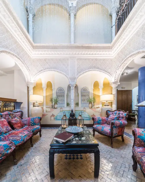 Sala de estar con arcos &aacute;rabes, sof&aacute;s coloridos y pared decorada.