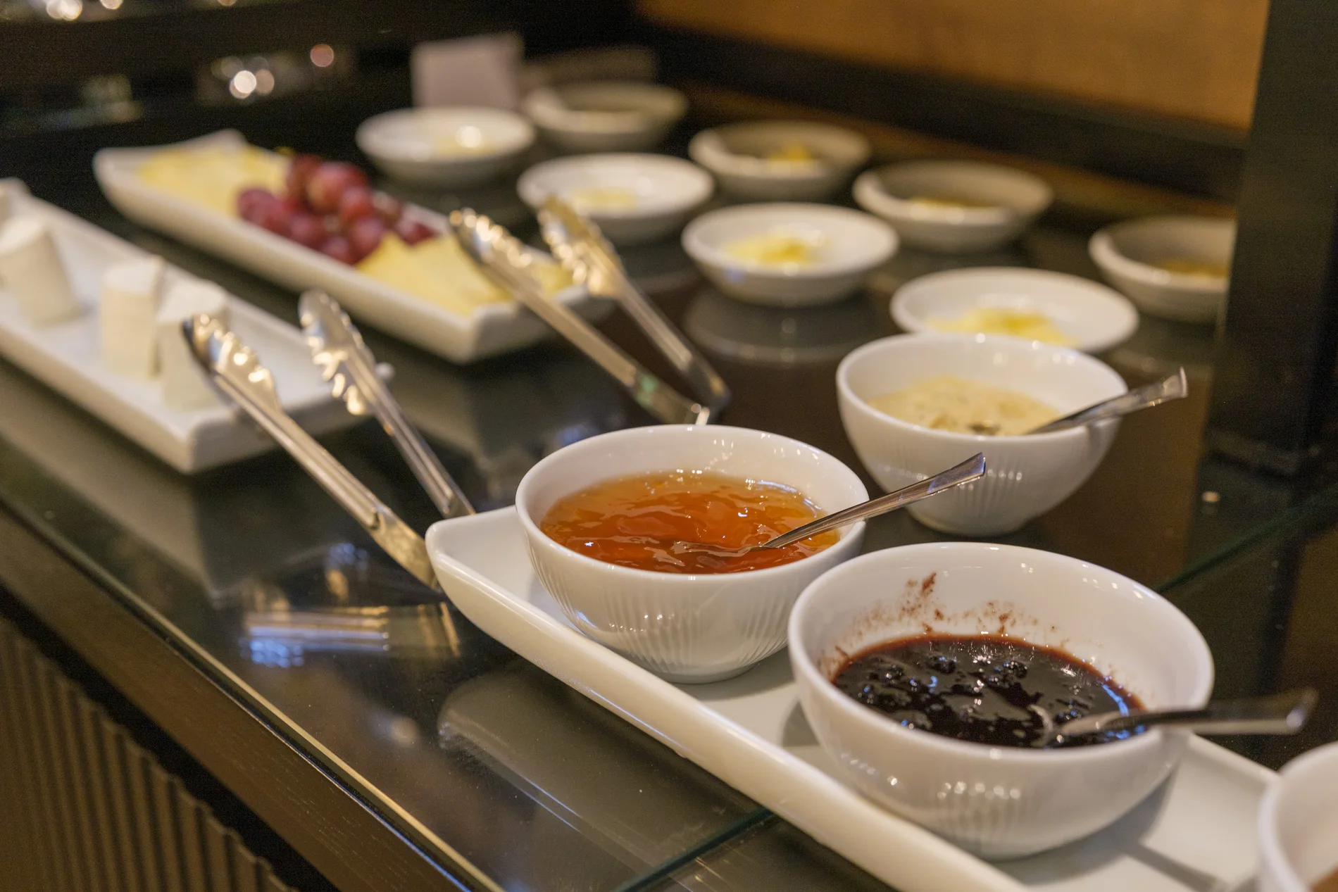 Pratos de geleias e acompanhamentos em um buffet elegante.