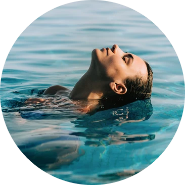 Mulher relaxando e flutuando na &aacute;gua com o rosto voltado para cima.