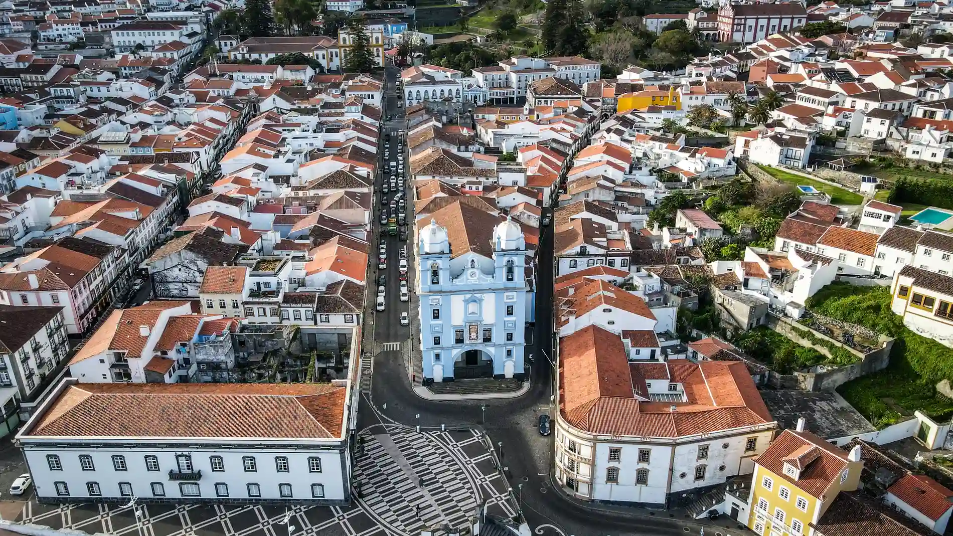 Vista a&eacute;rea de uma cidade com casas e igreja de telhados vermelhos.