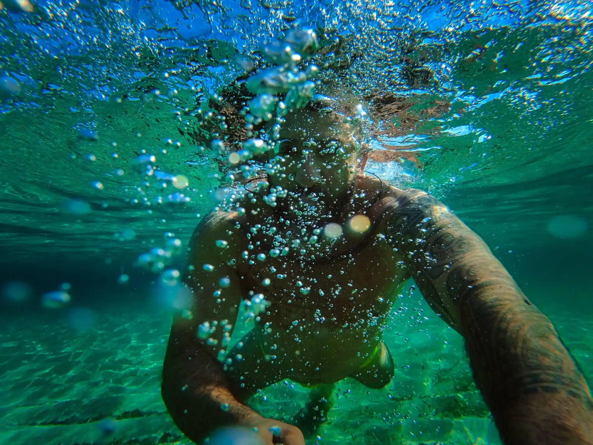 Pessoa nadando debaixo d'&aacute;gua com bolhas ao redor.