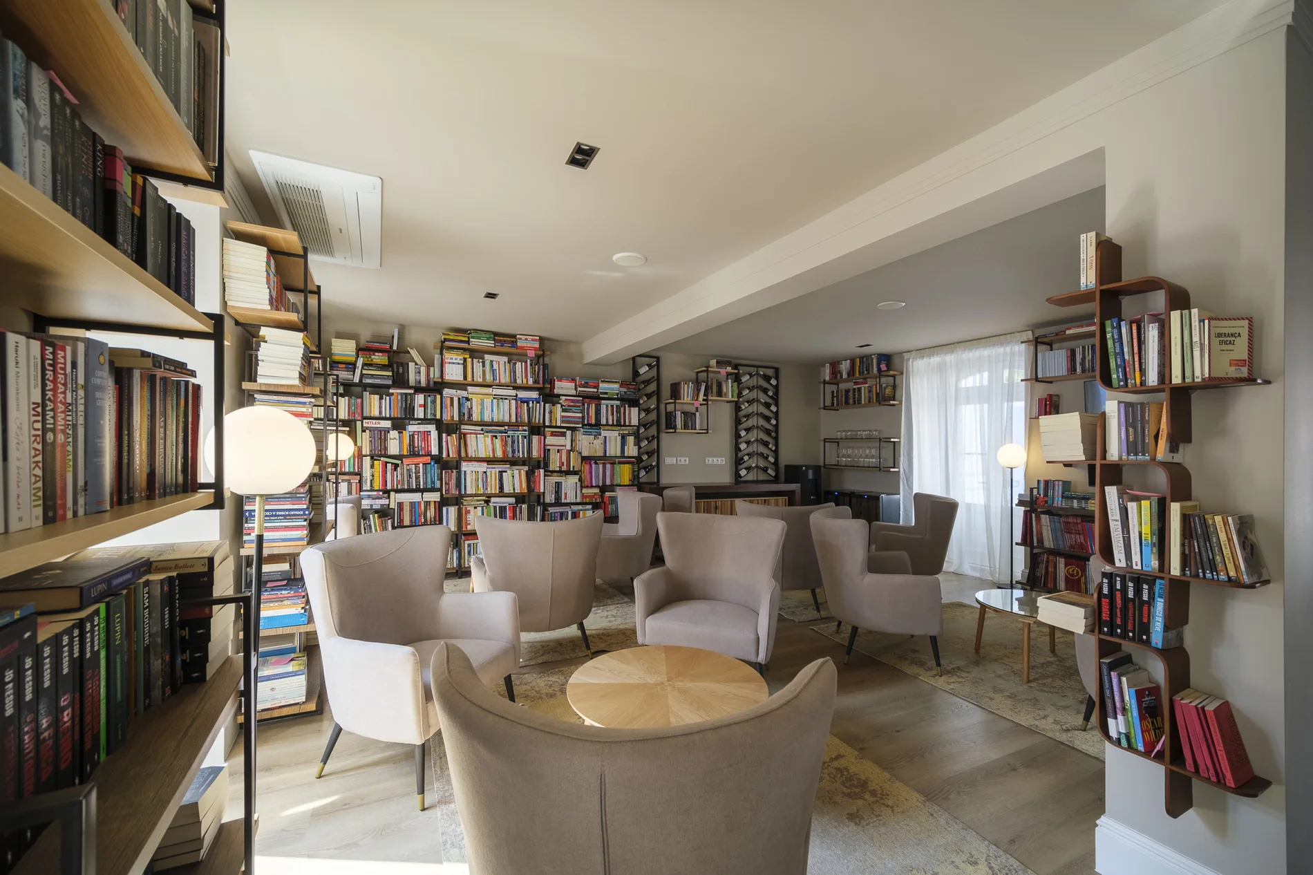 Sala de leitura aconchegante com poltronas e estantes cheias de livros.