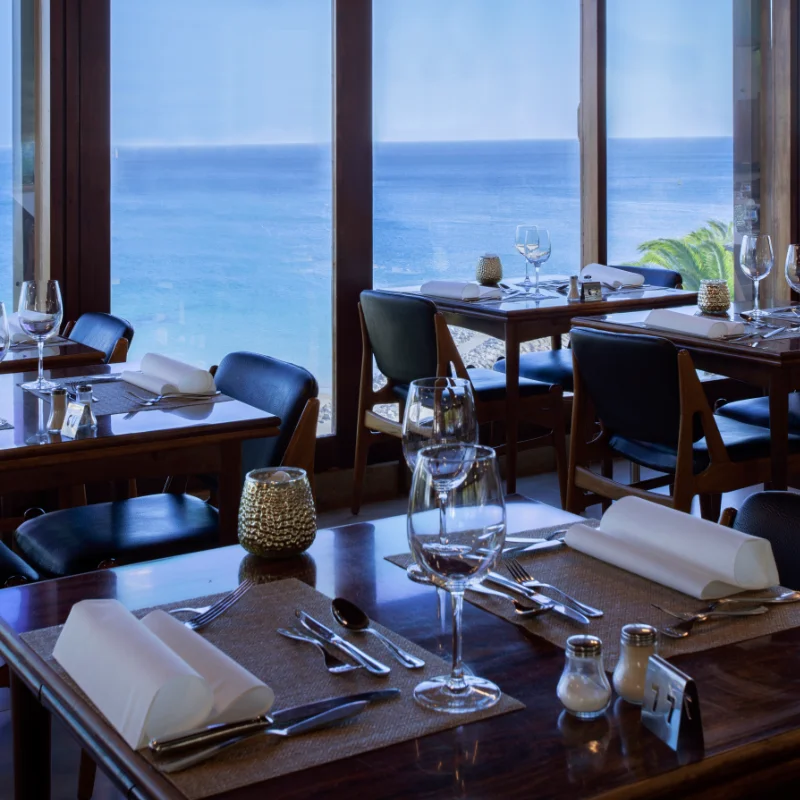 Restaurante com vista para o mar, mesas postas com eleg&acirc;ncia.