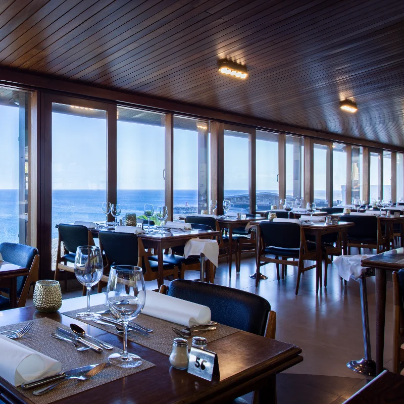 Restaurante &agrave; beira-mar com mesas prontas e vista panor&acirc;mica do oceano.