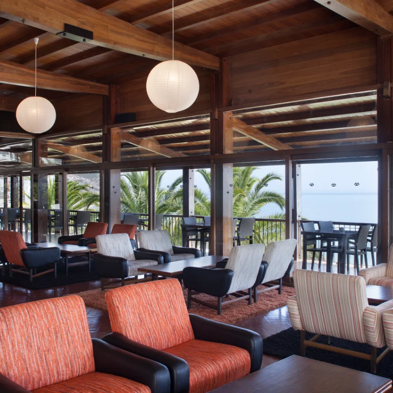 Sala de estar moderna com poltronas coloridas e vista para o mar.