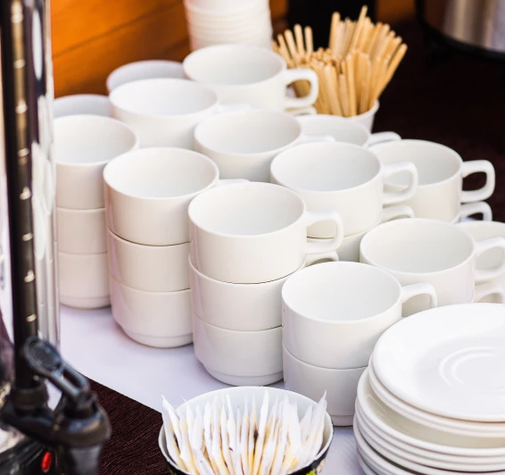 X&iacute;caras brancas empilhadas e palitos de madeira sobre uma mesa.
