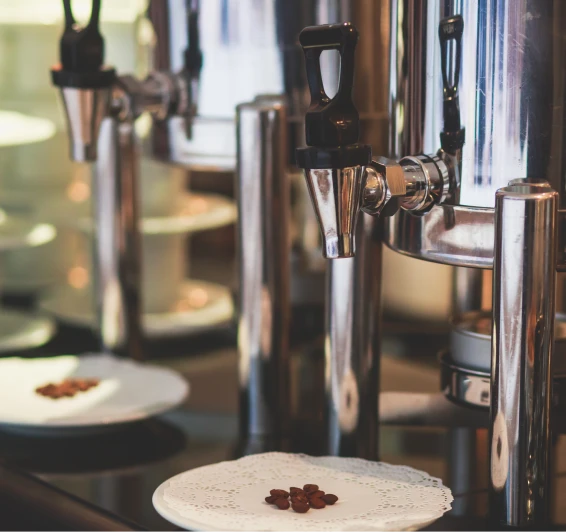 Dispenser de caf&eacute; com gr&atilde;os em pratos decorativos.