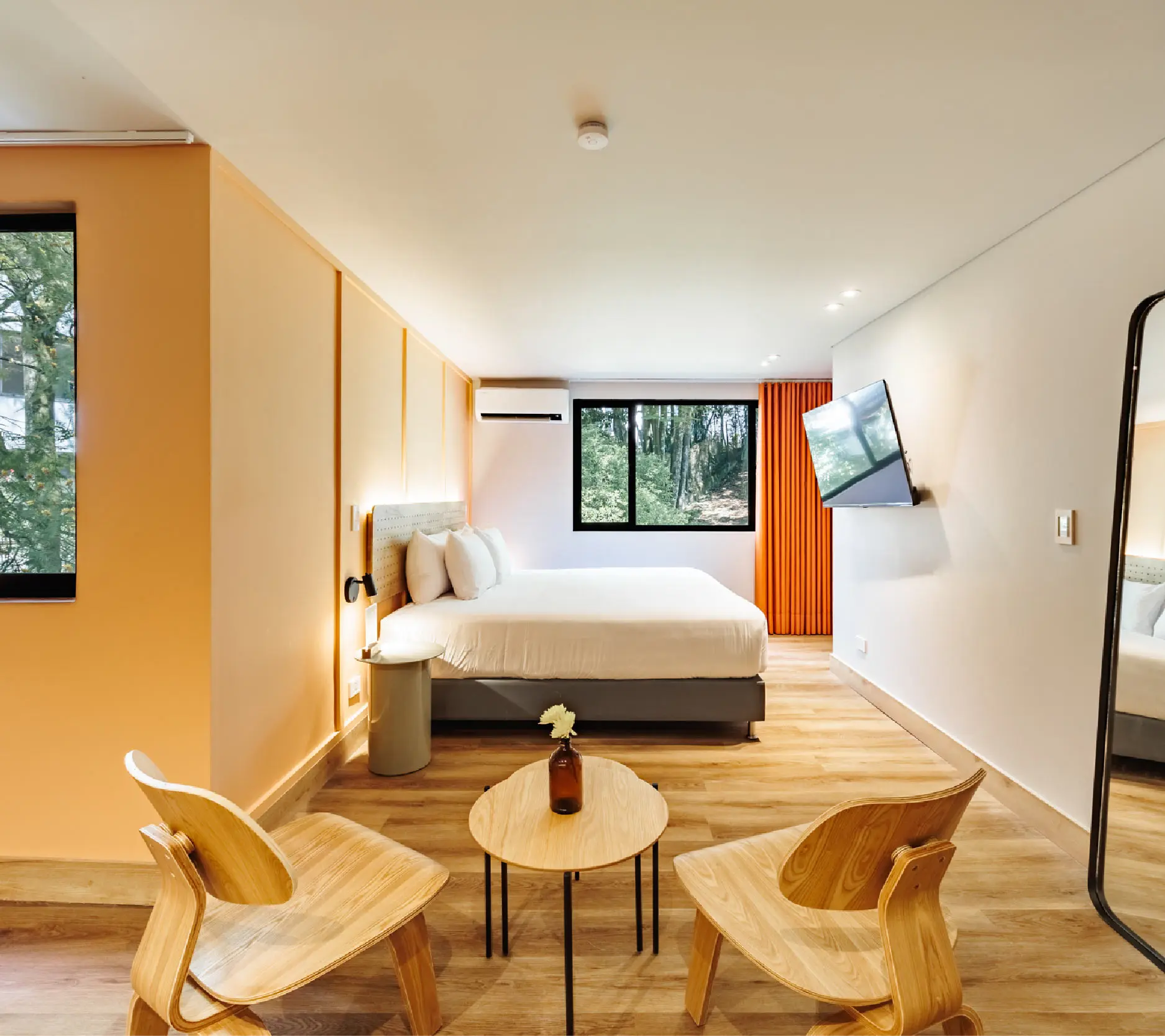 Habitaci&oacute;n moderna con cama, televisor y &aacute;rea de descanso.