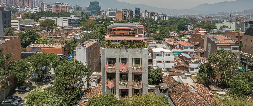 Edificio con terraza en zona urbana y monta&ntilde;as de fondo.