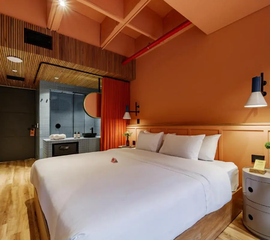 Habitaci&oacute;n de hotel moderna con cama grande y decoraci&oacute;n en tonos c&aacute;lidos.