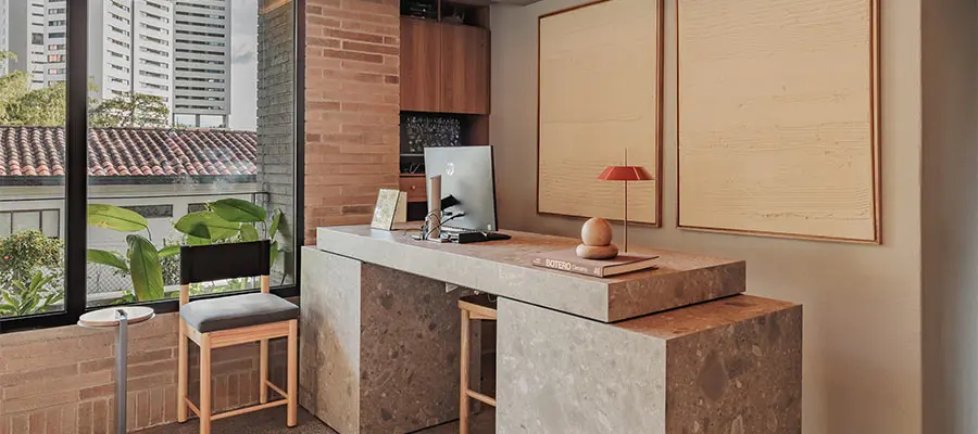 Oficina moderna con escritorio de m&aacute;rmol y silla frente a una ventana grande.