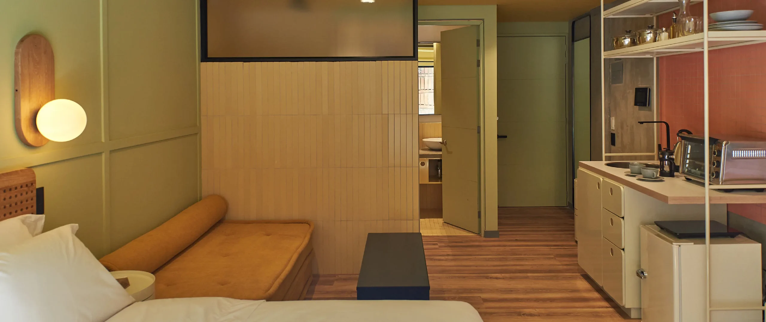 Habitaci&oacute;n acogedora con sof&aacute;, cocina integrada y puerta al ba&ntilde;o.