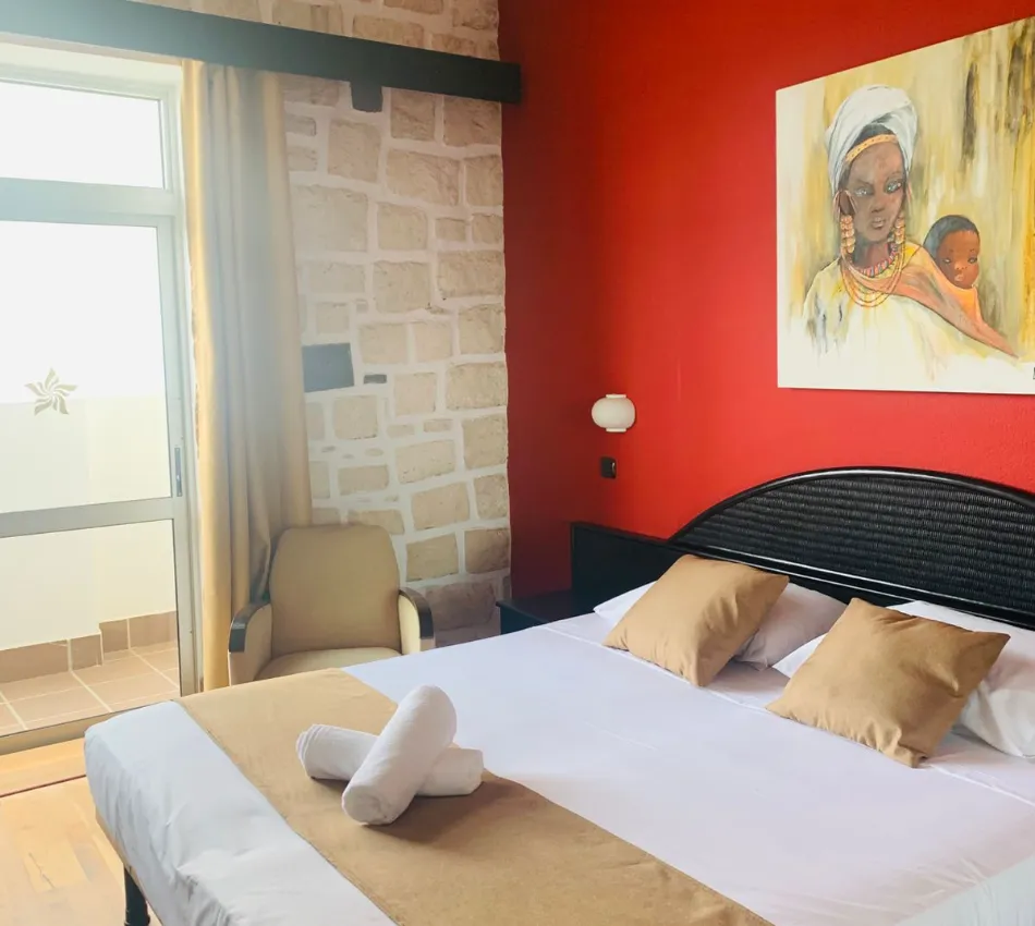 Quarto de hotel acolhedor com cama de casal, parede vermelha e pintura colorida na parede.