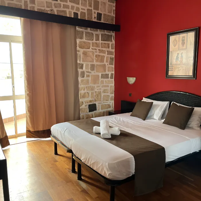 Quarto aconchegante com cama de casal, parede de pedra e decora&ccedil;&atilde;o moderna.