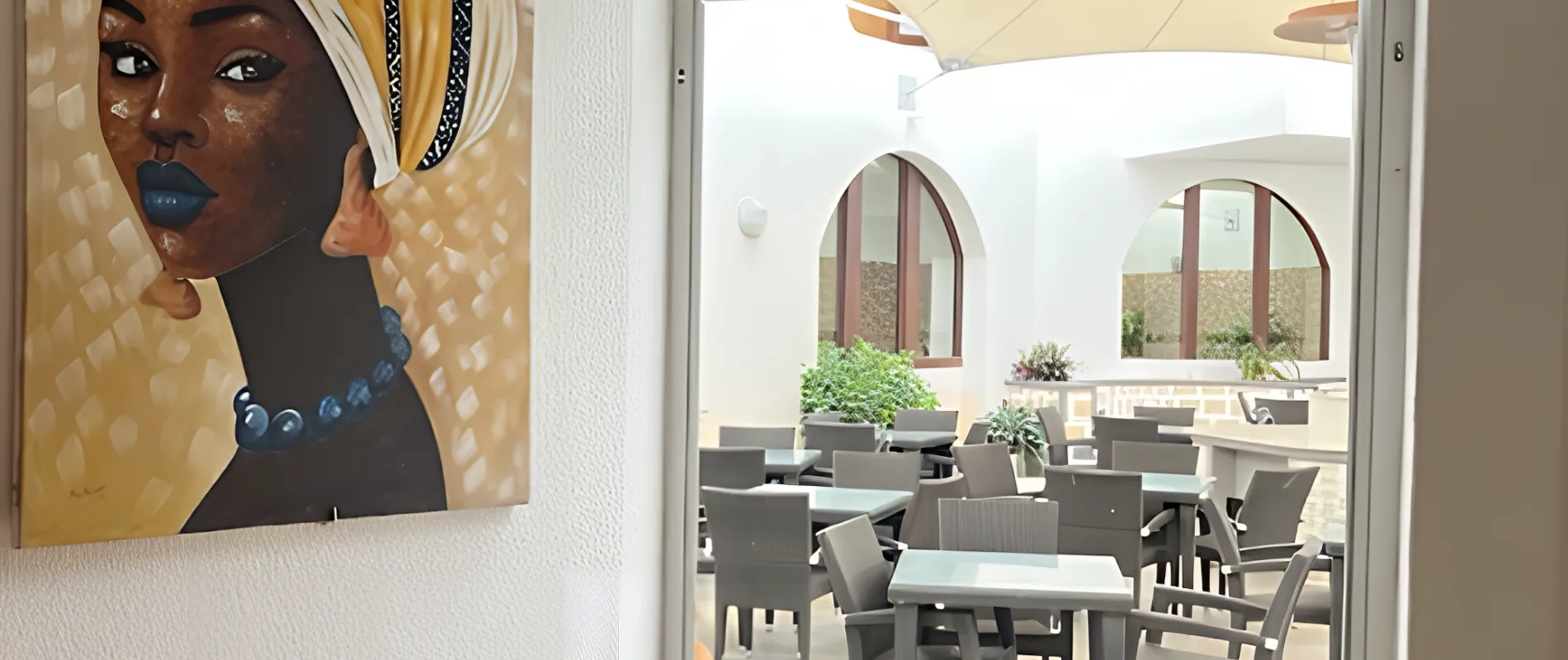 Pintura colorida de uma mulher e &aacute;rea externa com mesas e cadeiras sob uma cobertura.