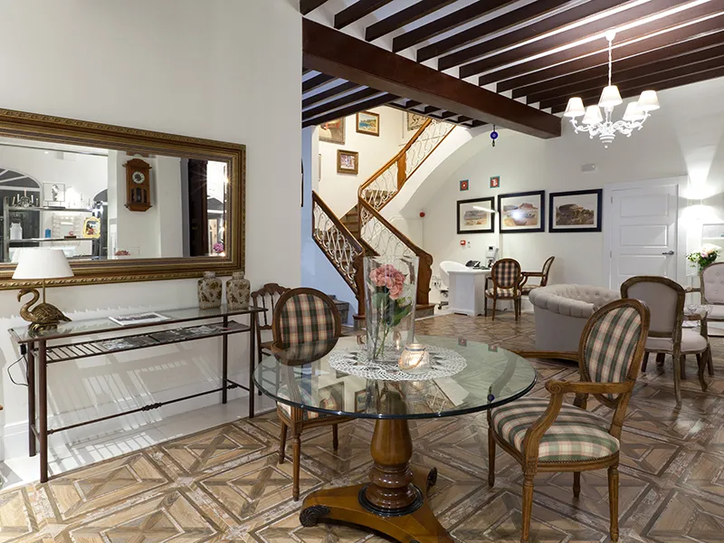 Sala de estar elegante, con muebles cl&aacute;sicos y una escalera decorativa.
