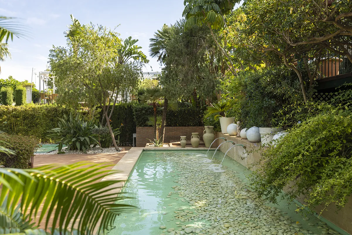Patio con piscina, plantas y jarrones decorativos.