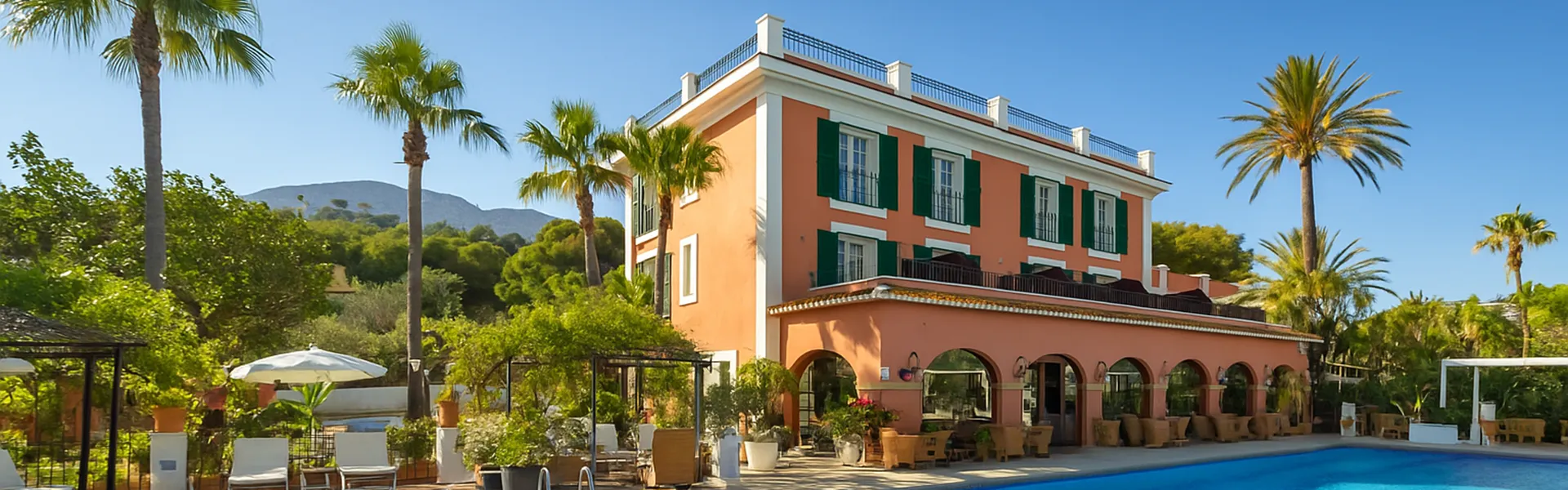 Edificio de tres pisos con palmeras y una piscina en el jard&iacute;n.