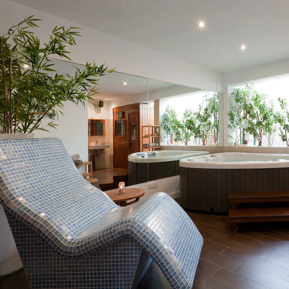 Spa moderno con jacuzzi, tumbona de azulejos y plantas decorativas.