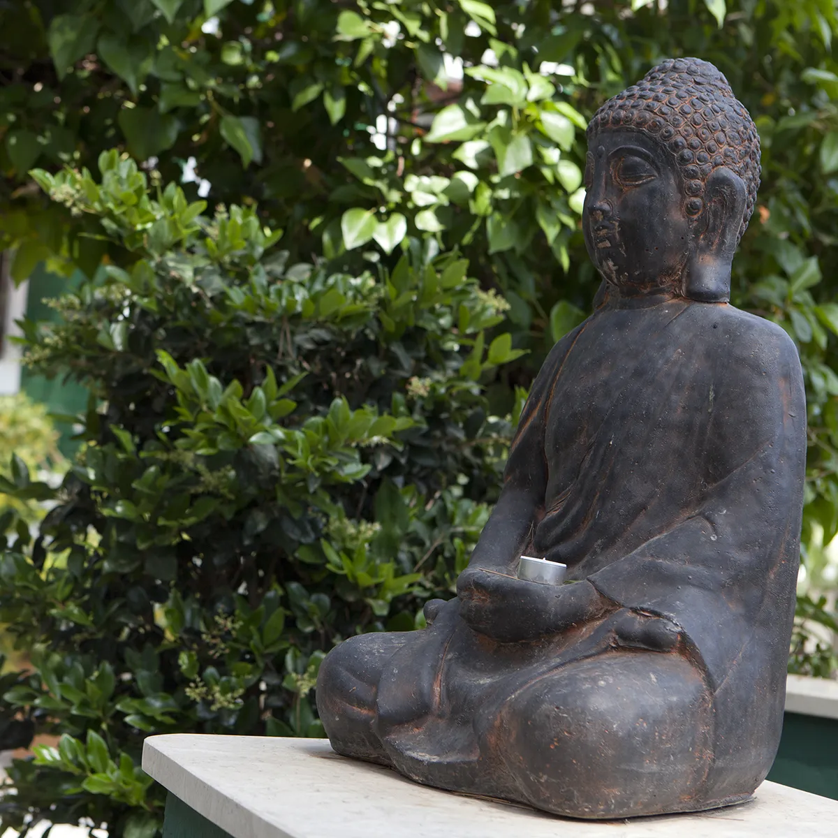 Estatua de Buda meditando en un jard&iacute;n verde.