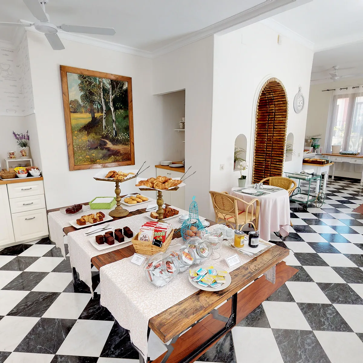 Desayuno buffet en mesa con panes y dulces en comedor elegante.