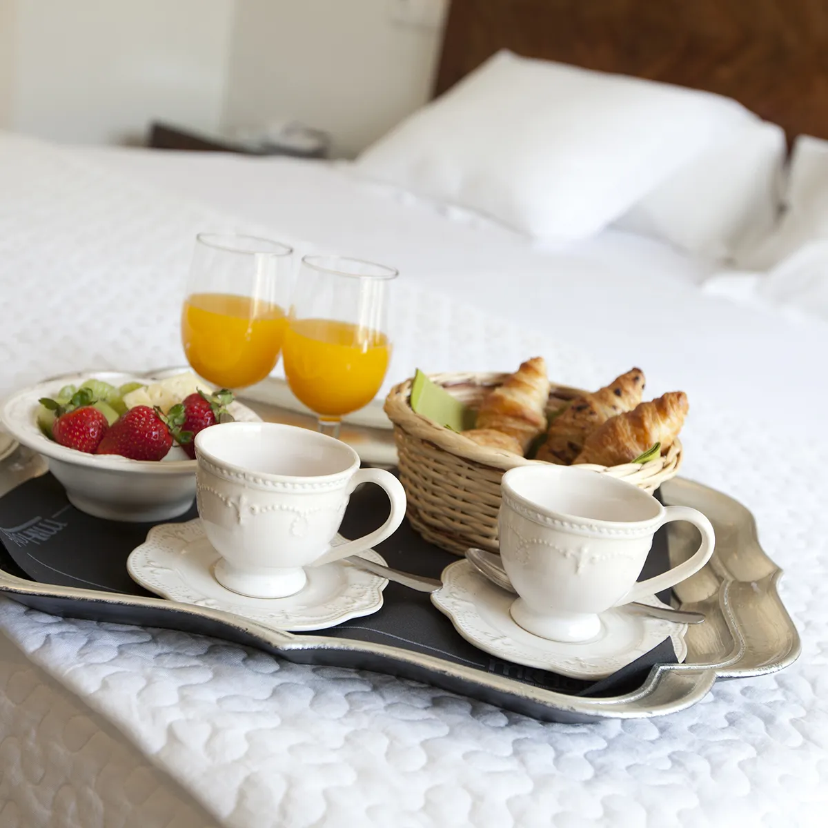 Desayuno en cama: caf&eacute;, croissants, frutas y jugo de naranja.