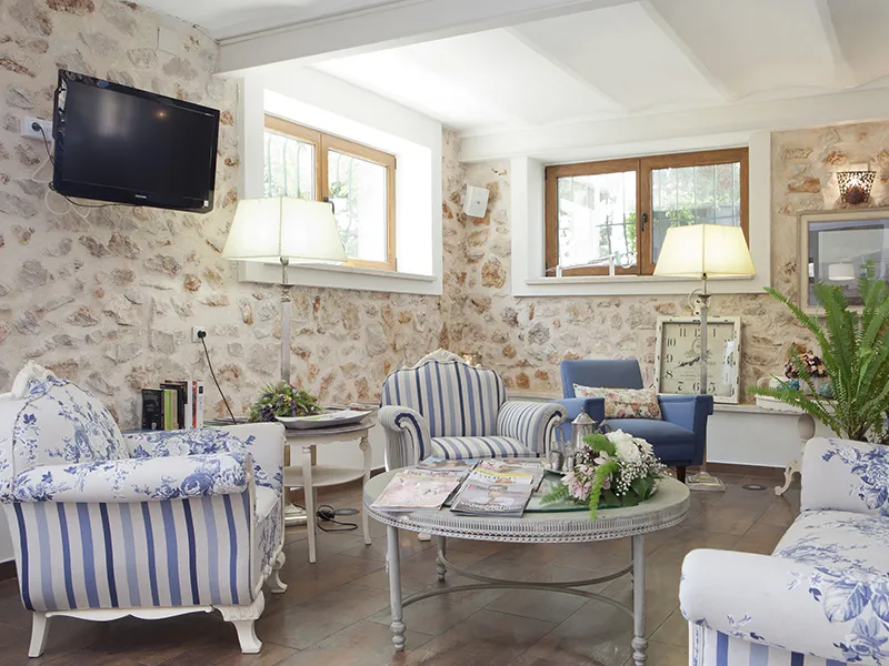 Sala acogedora con sillas de rayas, mesas redondas y flores decorativas.