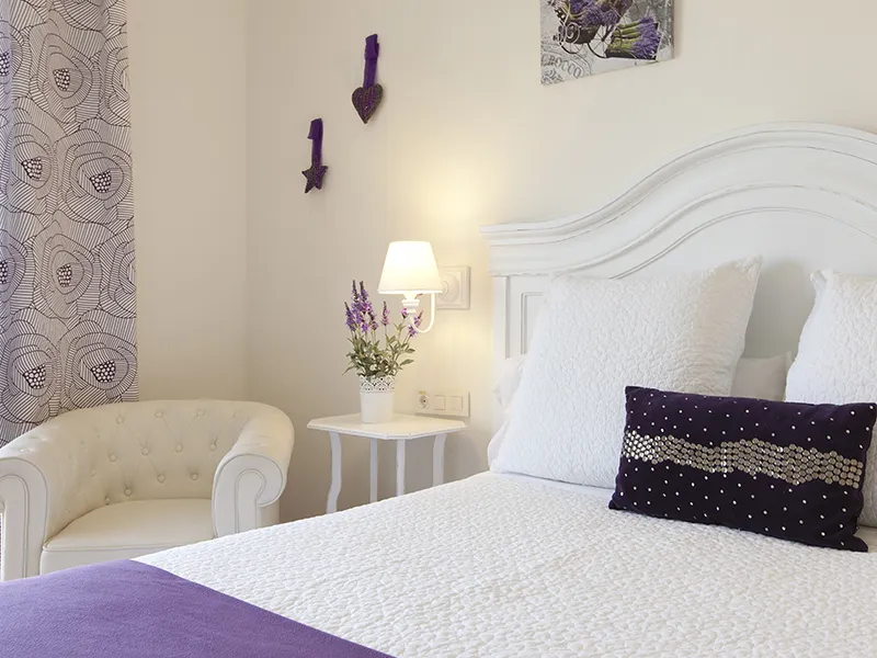 Habitaci&oacute;n acogedora con decoraci&oacute;n en blanco y morado.