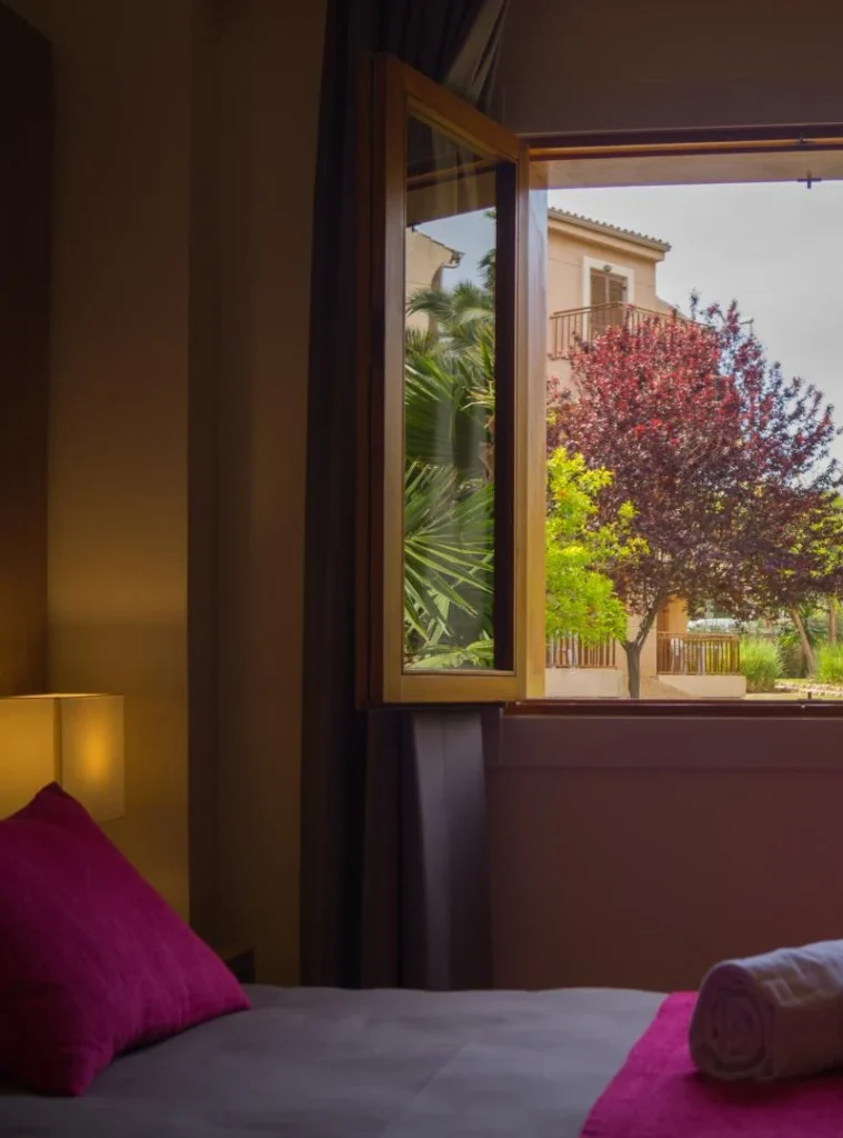 Habitaci&oacute;n con ventana abierta a un jard&iacute;n colorido.