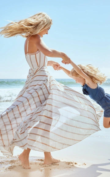 Madre e hija jugando en la playa bajo el sol.
