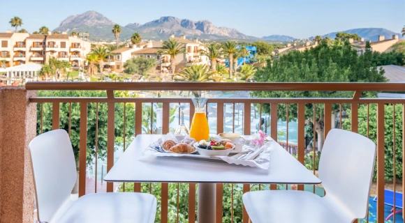 Desayuno en balc&oacute;n con vistas a las monta&ntilde;as y un pueblo.