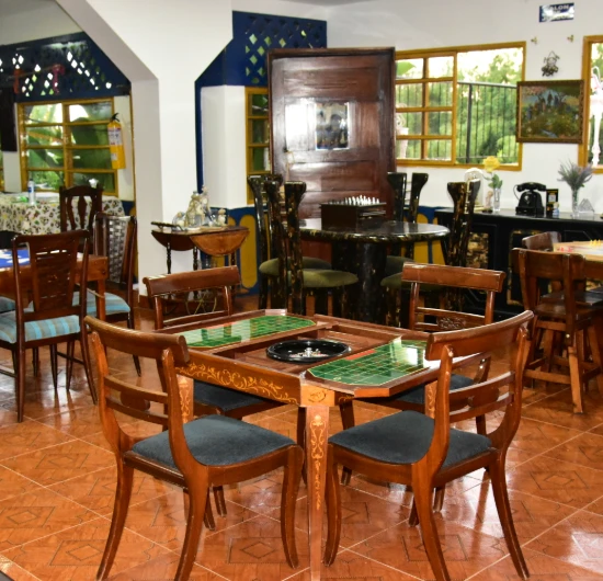 Sala con muebles de madera, mesa de juegos y ventanas al fondo.