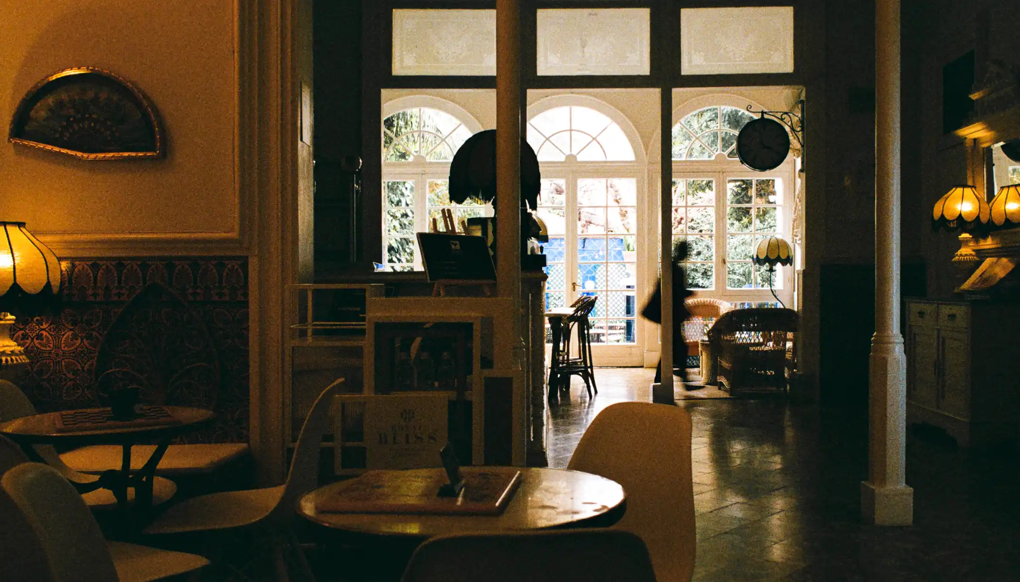 Cafeter&iacute;a acogedora con luz tenue y ventanales grandes.