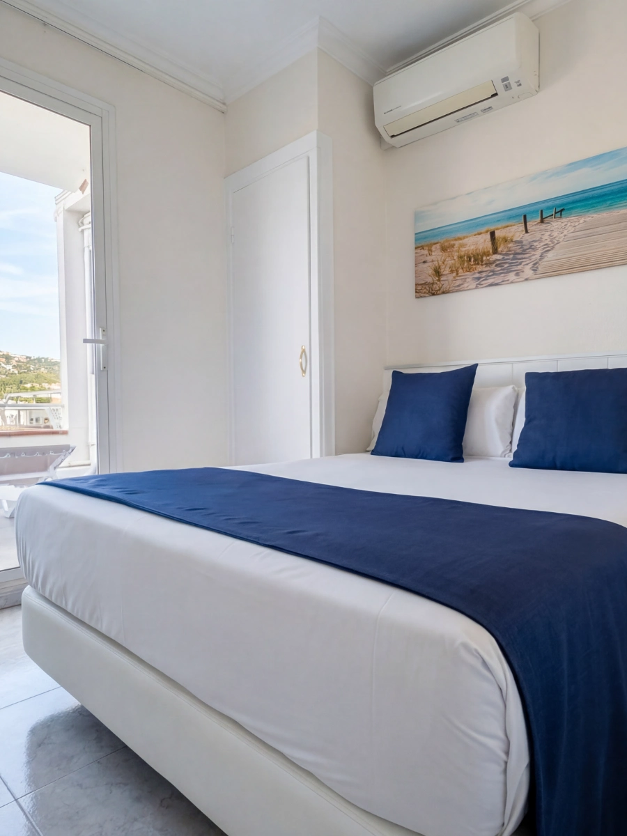Dormitorio moderno con cama doble, cojines azules y aire acondicionado en pared.
