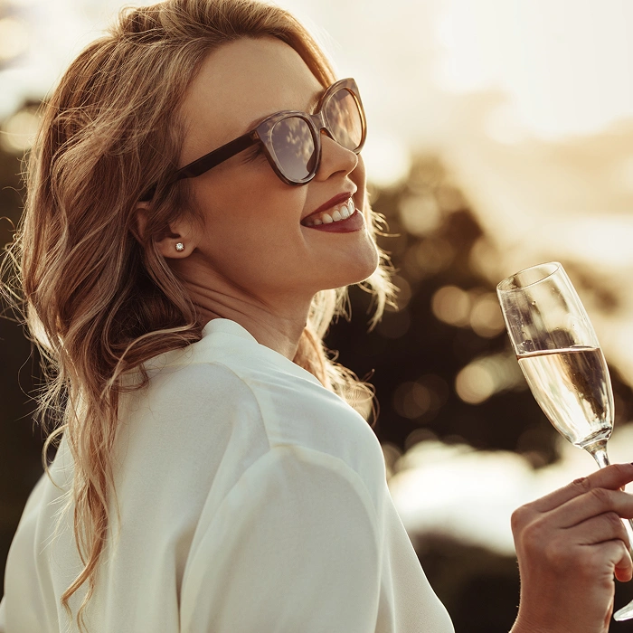 Mujer con gafas sonriendo y brindando con una copa de champ&aacute;n.