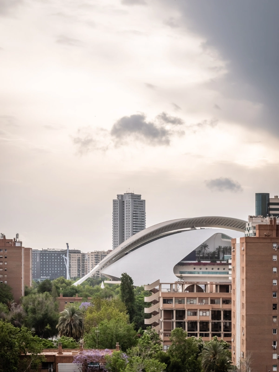Vista urbana con un edificio moderno y cielo nublado en el horizonte.