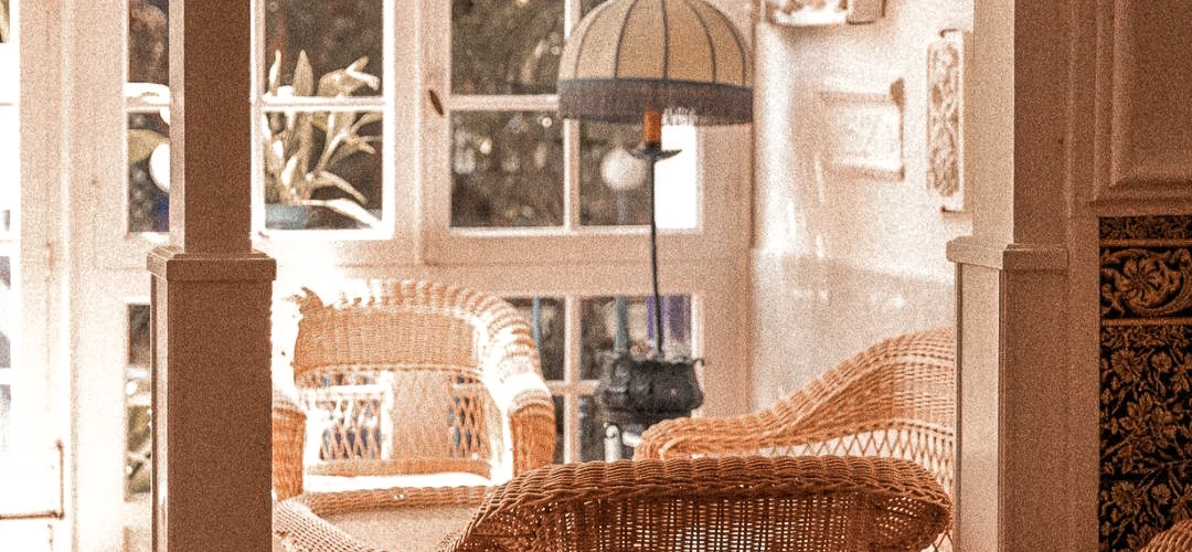 Sala luminosa con sillones de mimbre y l&aacute;mpara, junto a un ventanal.
