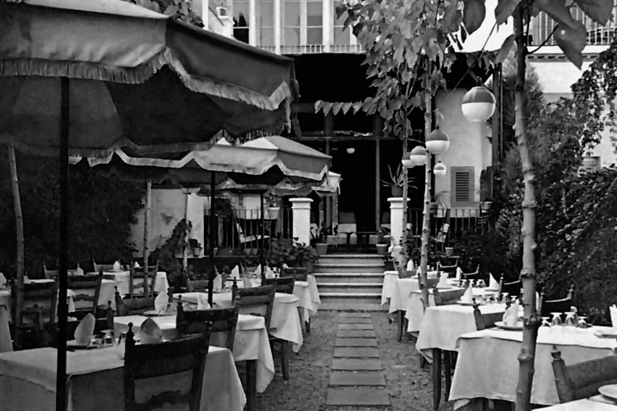 Restaurante al aire libre con mesas y sombrillas, estilo vintage en blanco y negro.