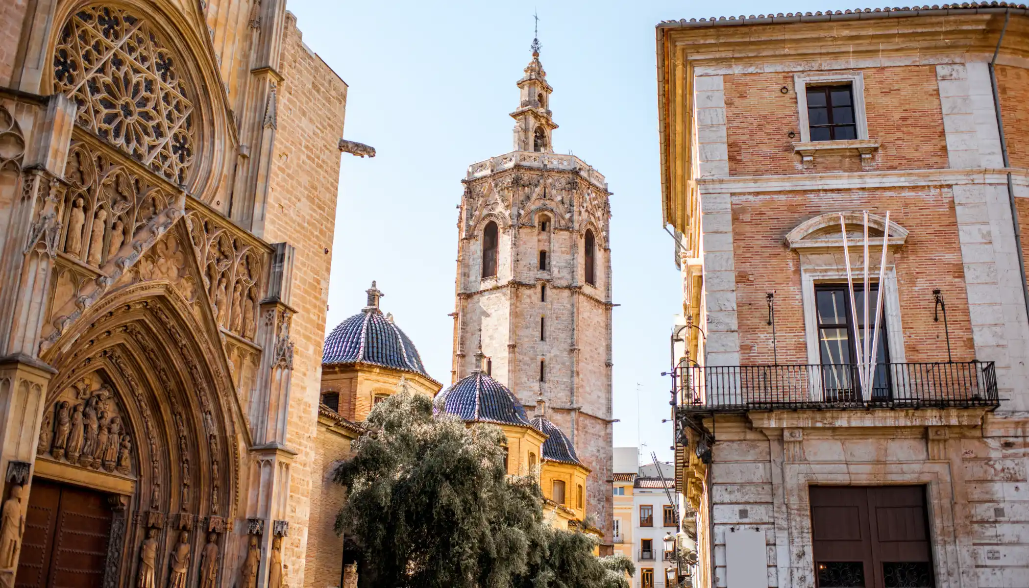Catedral g&oacute;tica con torre y edificios antiguos bajo un cielo despejado.