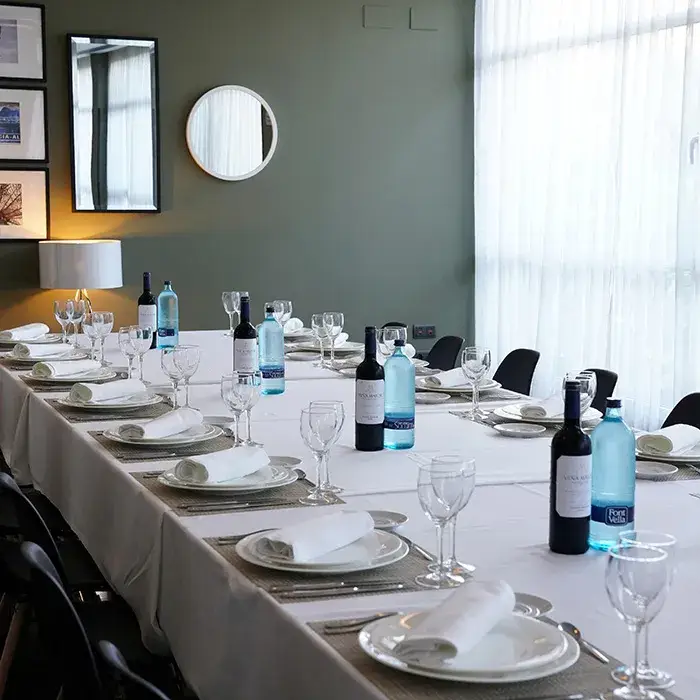 Mesa elegante con copas y botellas de vino en una sala con luz natural.