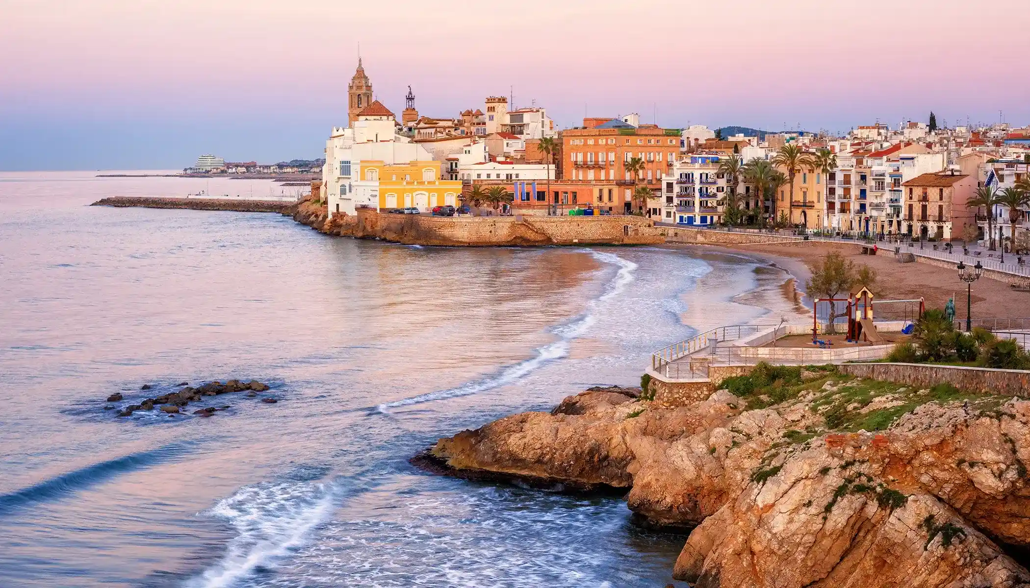 Atardecer en una costa con casas coloridas y una iglesia cerca del mar.