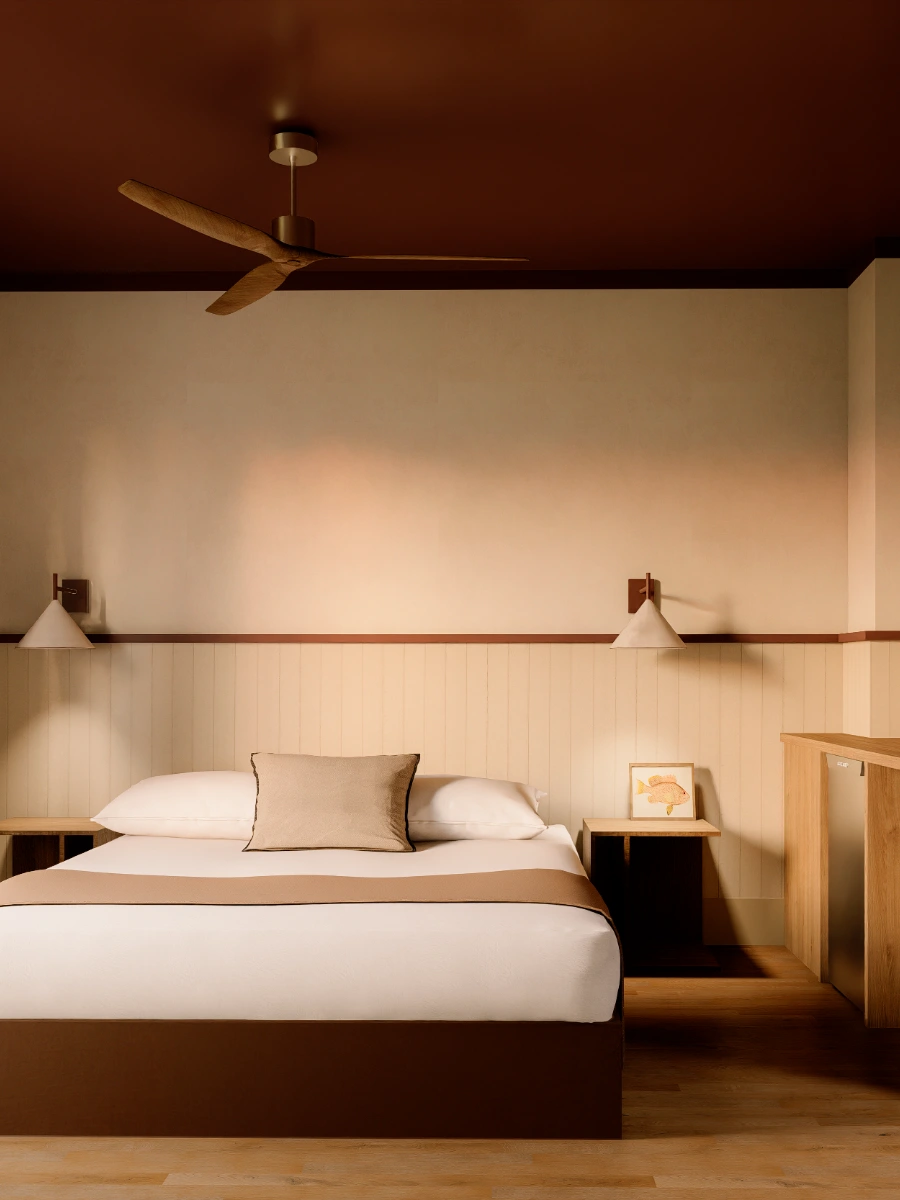 Habitaci&oacute;n minimalista con cama, coj&iacute;n, l&aacute;mparas y ventilador en techo marr&oacute;n.